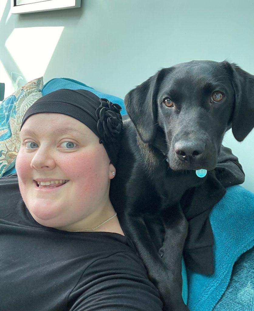 Photo of Tasha, who has Behçet's, with her therapy dog - a black labrador called Luna Rose