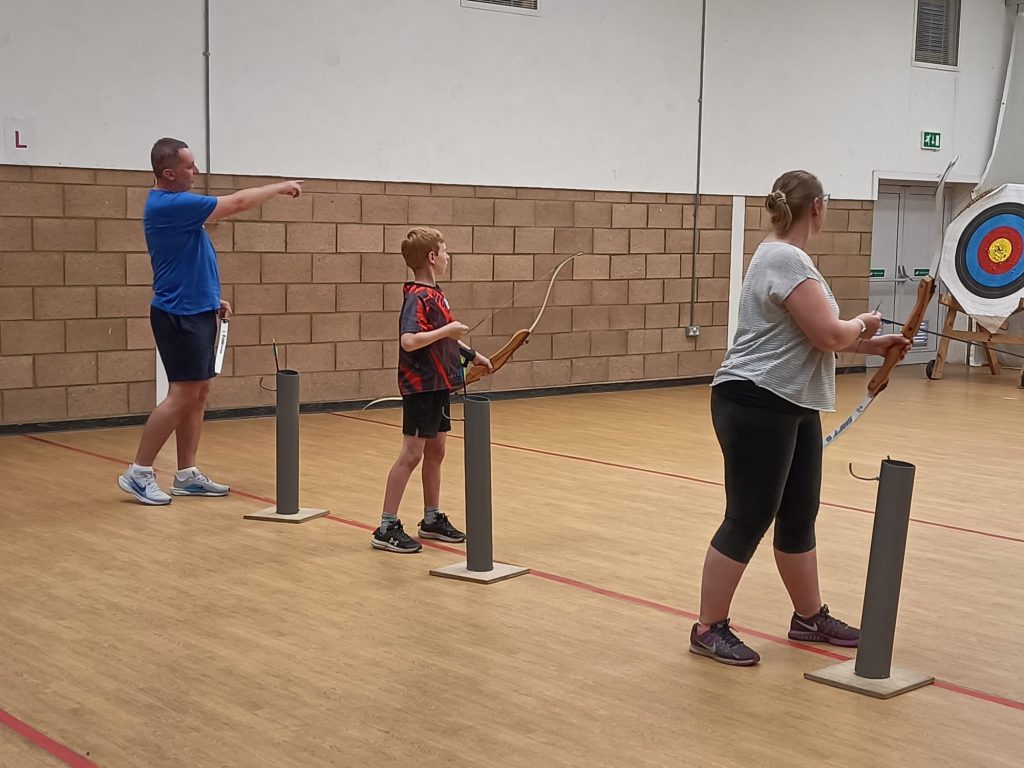 Three of our guests taking part in archery in the indoor auditorium. You can see on of the targets in the background.